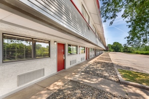 A building with a row of windows, a red door, and a parking lot. - Red Roof Inn Erie – I-90 (Erie)