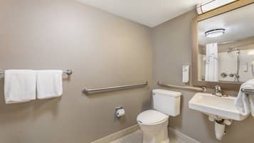 A standard hotel bathroom with a toilet, sink, and hand soap dispenser.