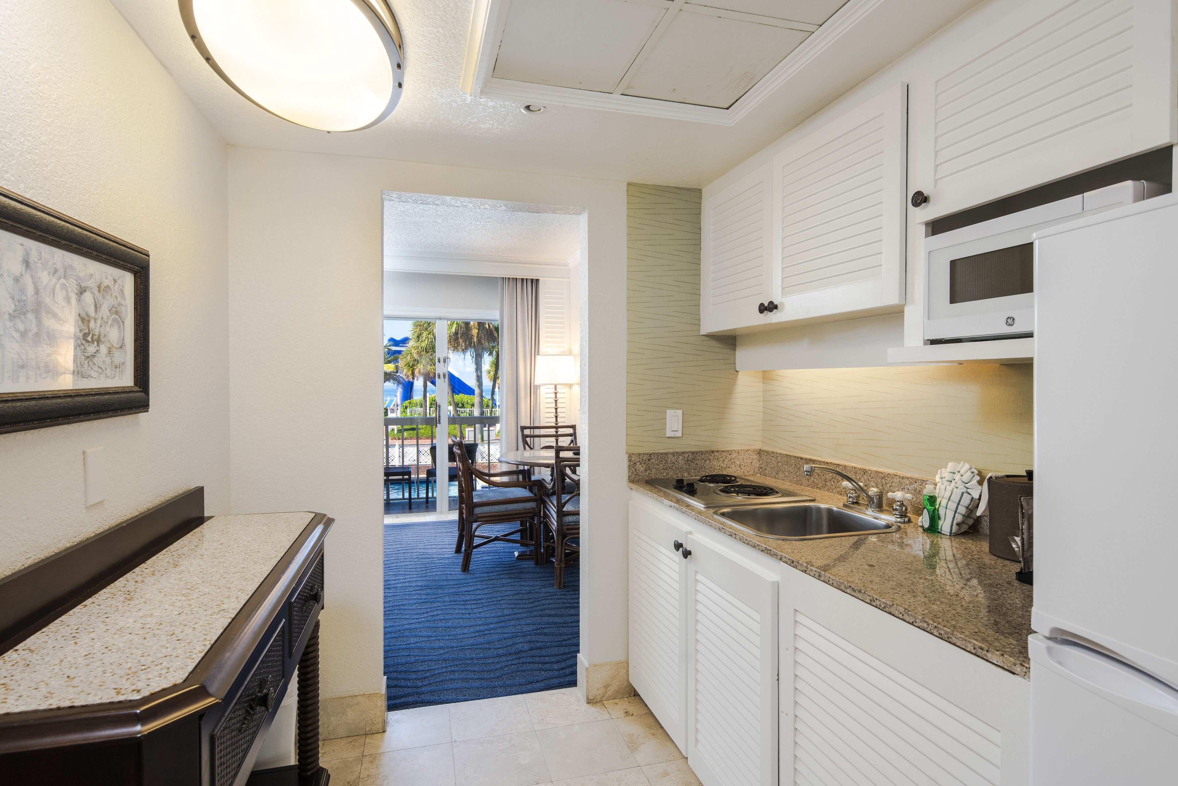 A kitchen with white cabinets, a granite countertop, a microwave, and a sink.
