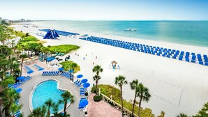 Un complexe hôtelier en bord de mer doté d’une piscine, de chaises longues et offrant une vue dégagée sur l’océan.