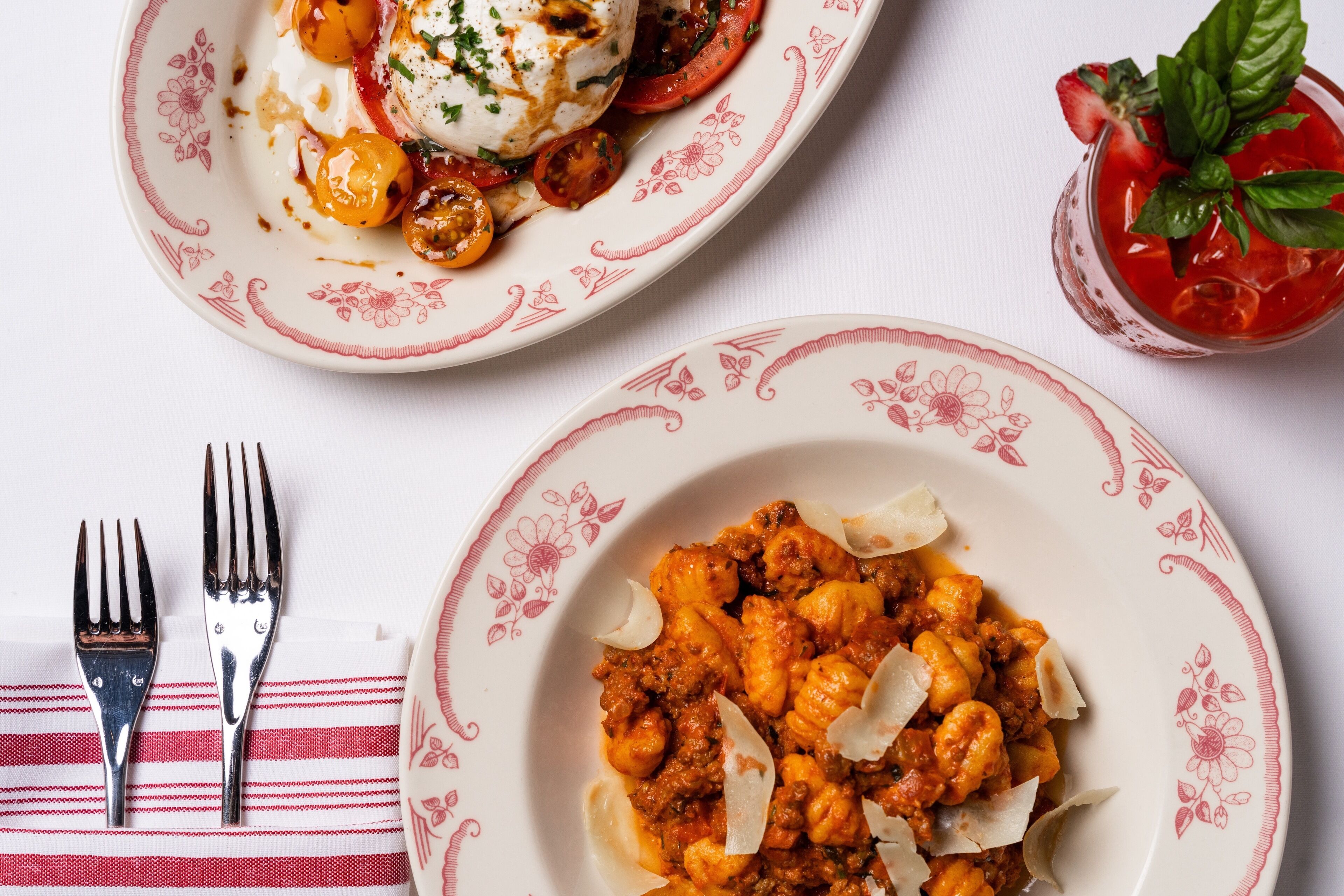 Two plates of food on a table with a striped napkin and two forks.