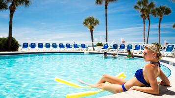 Relax by the pool surrounded by lush palm trees and comfortable lounge chairs.
