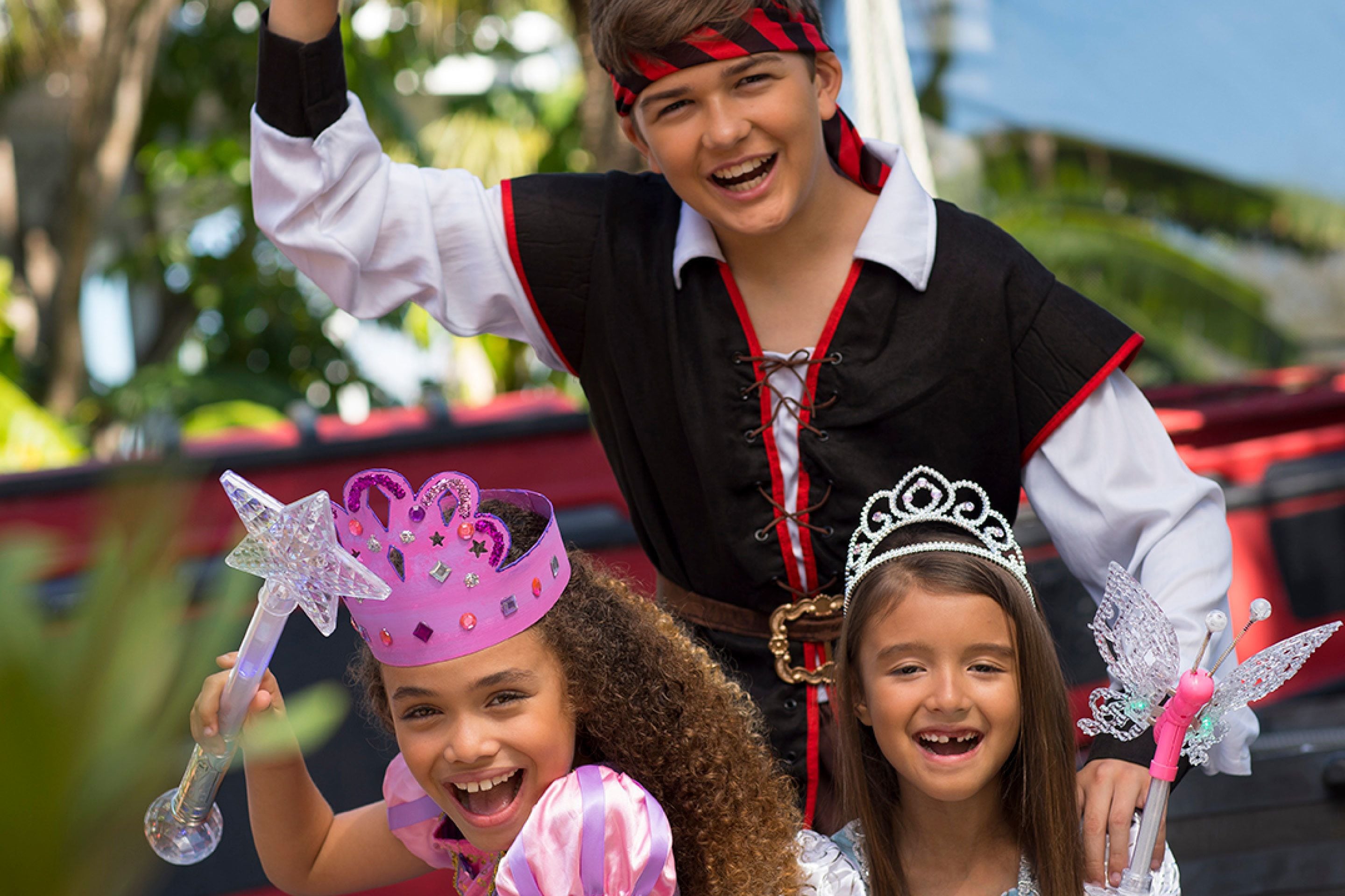 A group of people in festive costumes with a red vehicle in the background.