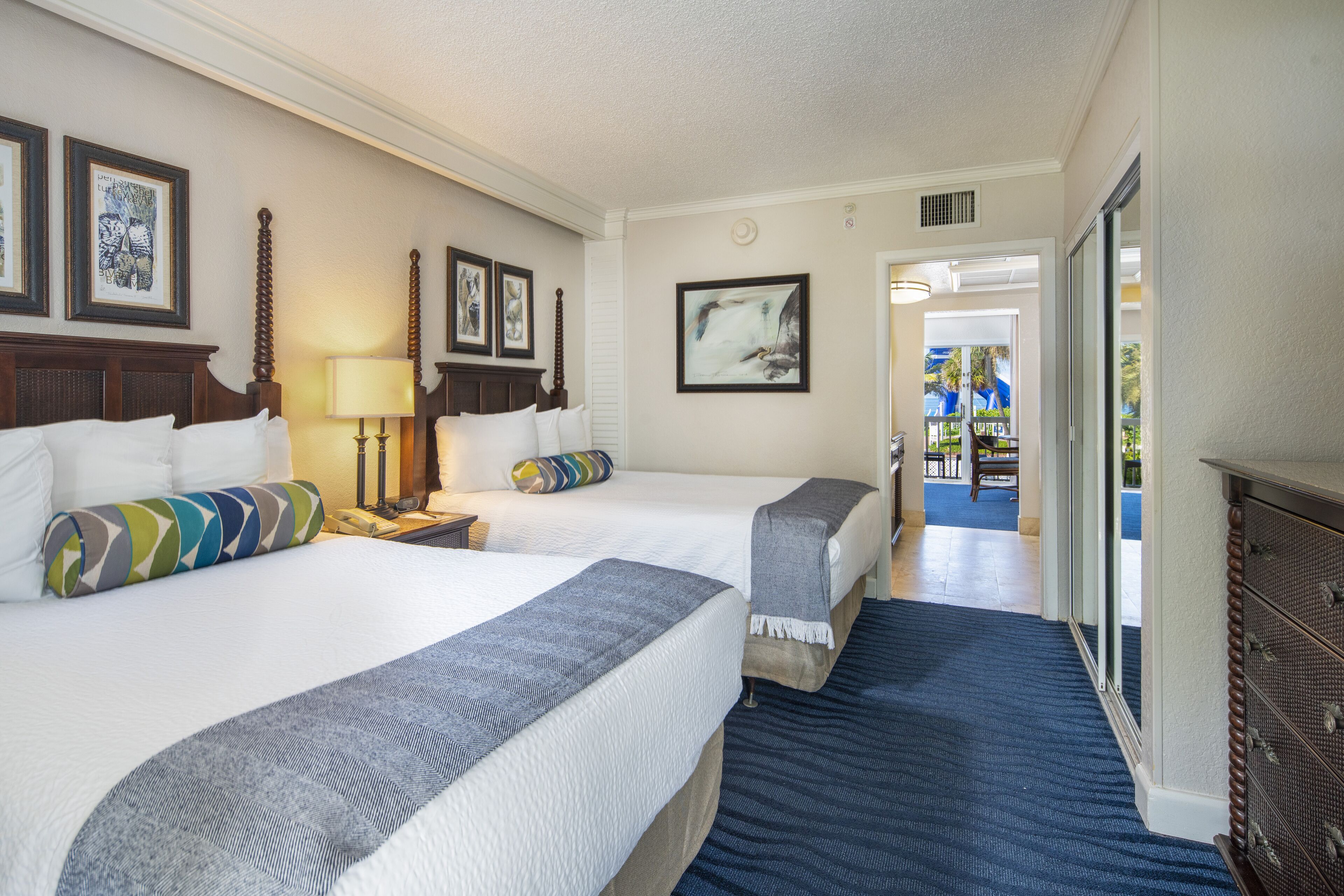 A hotel room with two beds, a large window, and a view of the outdoors.