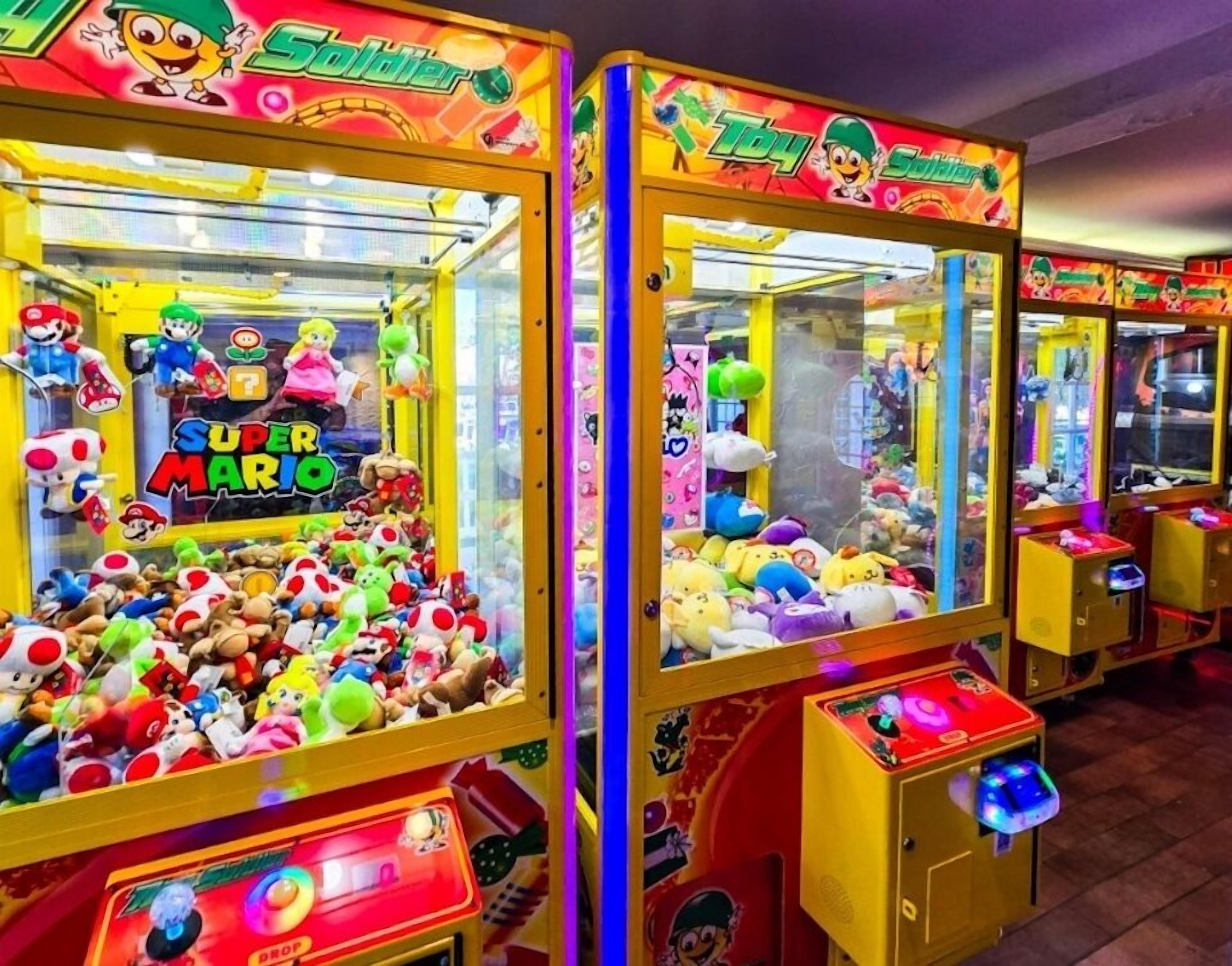 Eine Reihe von hell erleuchteten Krabschere-Automaten, gefüllt mit Stofftieren und beschriftet mit verschiedenen Videospiel-Figuren.