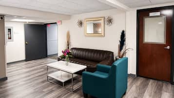 A reception area with a leather couch, teal armchair, and a white coffee table.