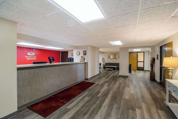A hotel reception area with a red wall, a reception desk, and a wooden floor.