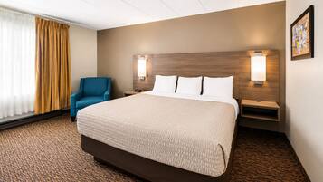 A hotel room with a large bed, two bedside tables, a chair, and a window with curtains.