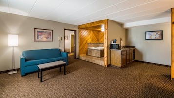 Une chambre d’hôtel avec un canapé bleu, une petite table, un meuble en bois et un tableau au mur.