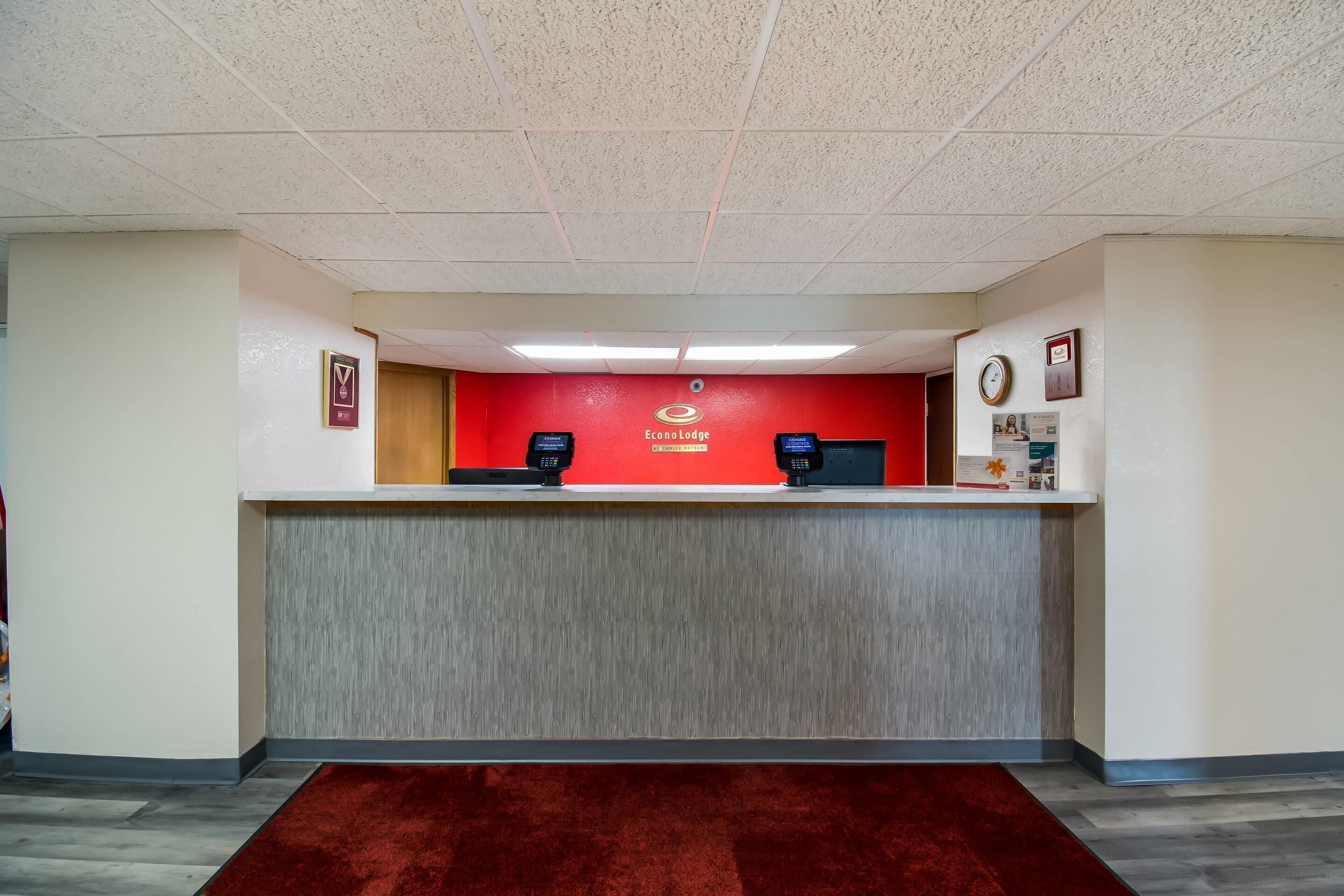 Ein Empfangsschalter mit roter Wand, zwei Chipkartenlesegeräten und einer Wanduhr.