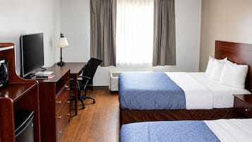 Een hotelkamer met een bed, een bureau met stoel, een televisie en een raam met gordijnen.