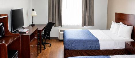Quarto de hotel com cama, secretária e cadeira, televisão e janela com cortinas.