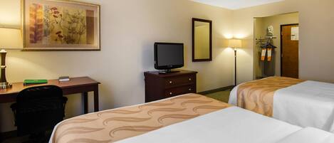 A hotel room with two beds, a desk with a computer, a television, and a painting on the wall.