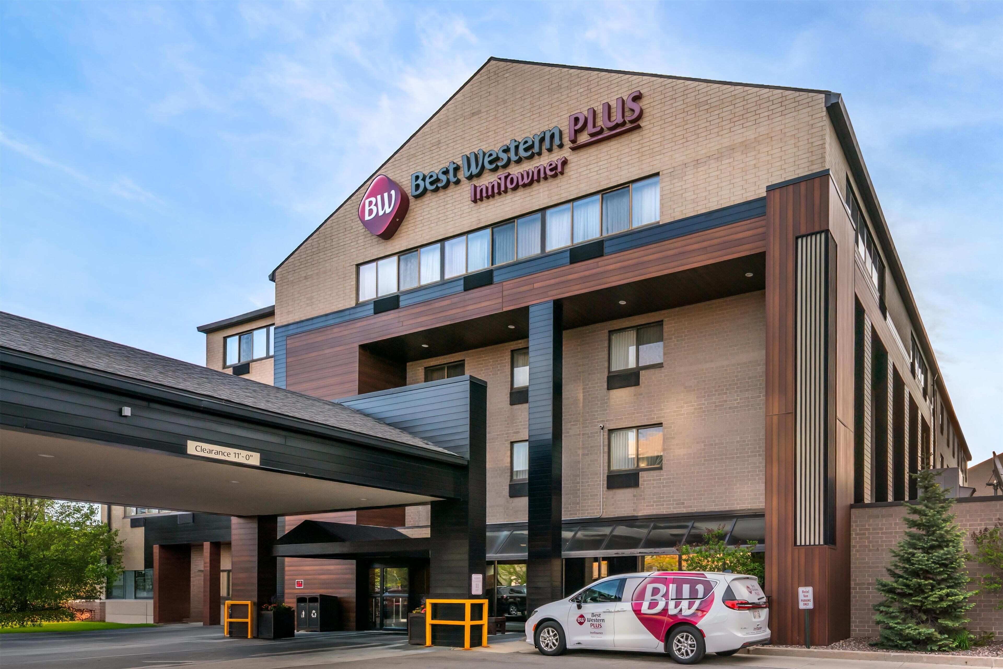 Un bâtiment de la chaîne Best Western Plus InnTownier, avec une entrée bien visible, un espace de stationnement couvert et un fourgon de livraison garé à l’extérieur.