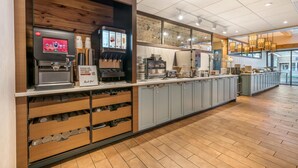 A coffee station with a digital coffee machine, a coffee cup dispenser, and a sign instructing to use the cups for coffee.