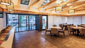 A restaurant with a buffet, wooden ceiling, and large windows overlooking the street. - Best Western Plus InnTowner Madison (Madison)