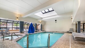 An indoor swimming pool with a tiled floor, a skylight, and a clock on the wall.