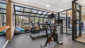 A gym with exercise equipment, large windows, and a view of the outside. - Best Western Plus InnTowner Madison (Madison)