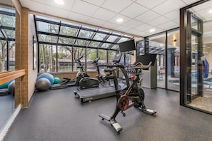 A gym with exercise equipment, large windows, and a view of the outside.