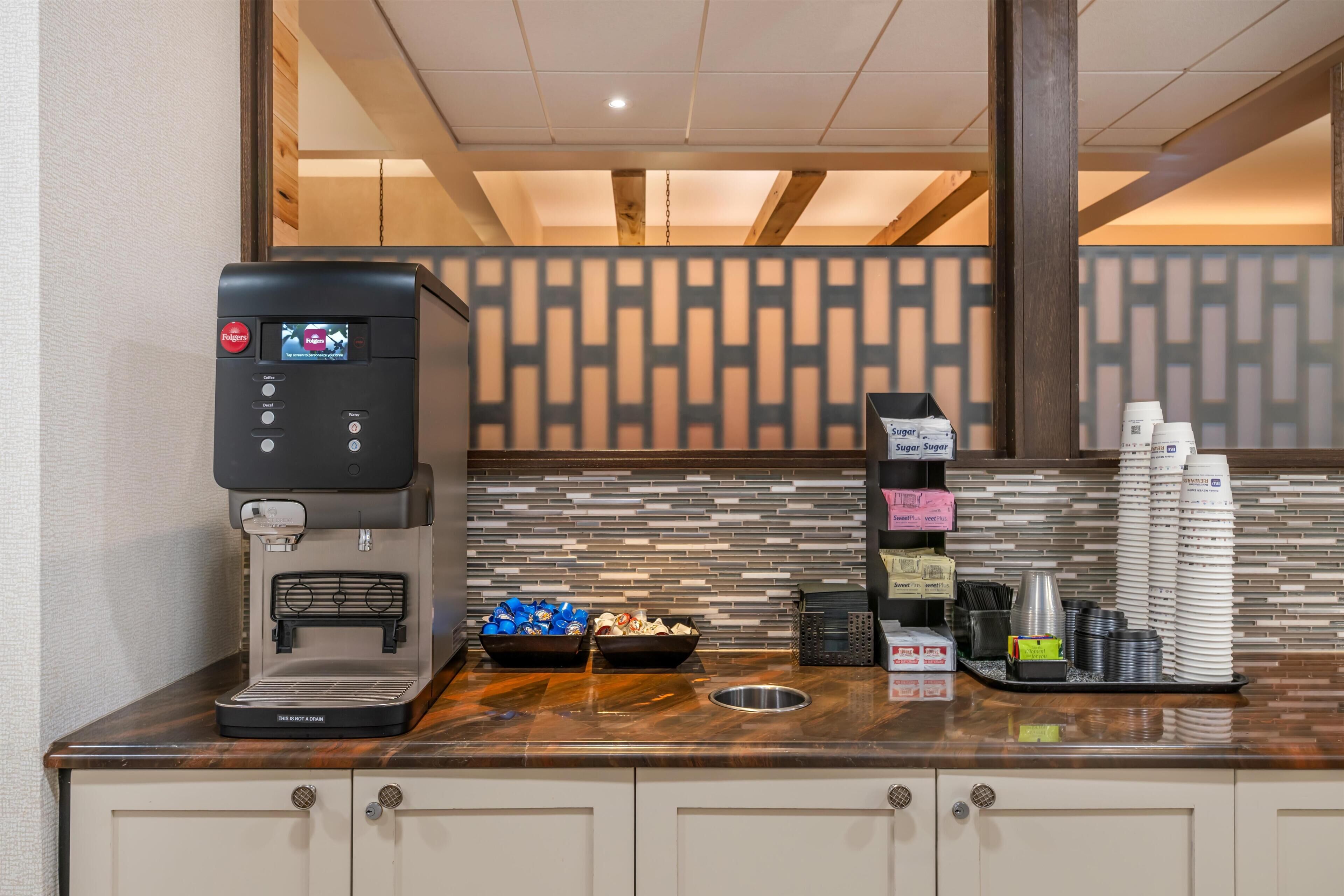 A coffee station with a coffee machine, sugar, creamer, and napkins.