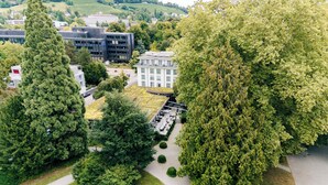 An aerial view of a campus with modern buildings, green spaces, and a large tree. - Park Hotel Winterthur (Winterthur)