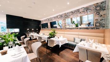 A restaurant with white tablecloths, cushioned booths, and a patterned wall.