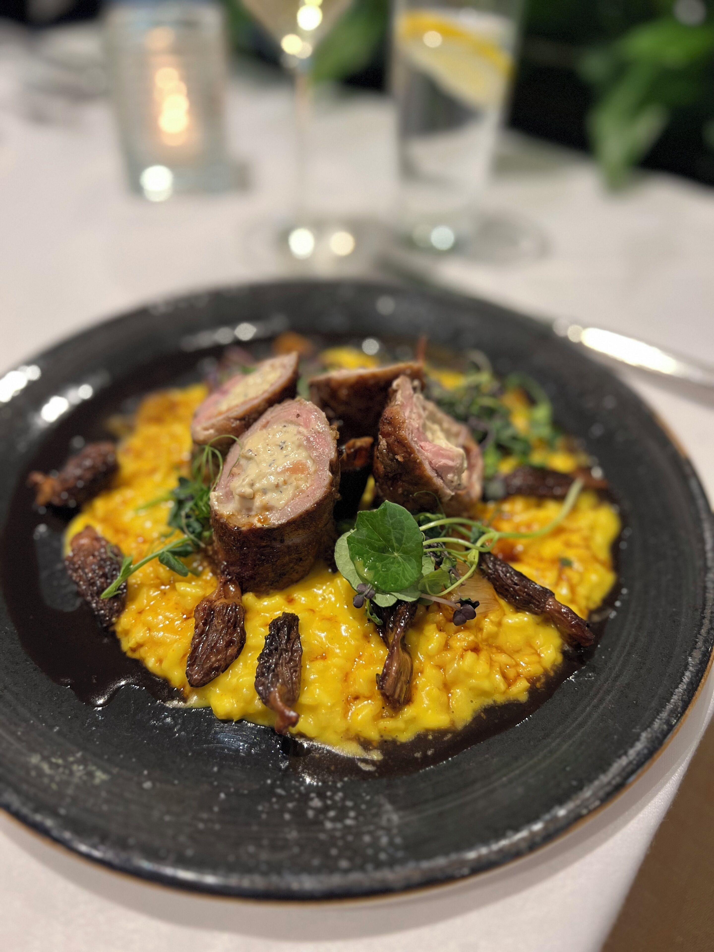 A plate of food with a black plate, yellow sauce, and meat slices.