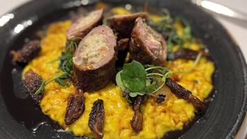 A plate of food with a black plate, yellow sauce, and meat slices.