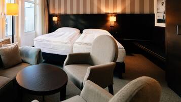 Une chambre d’hôtel avec un lit, deux fauteuils, une petite table et un canapé.