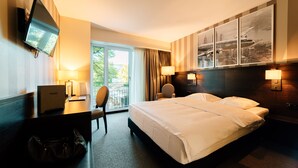 A hotel room with a bed, desk, chair, TV, and a view of the outdoors. - Park Hotel Winterthur (Winterthur)