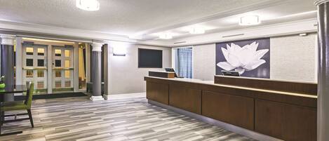 Un área de recepción con un mostrador de madera, una gran decoración floral en la pared y un suelo estampado.