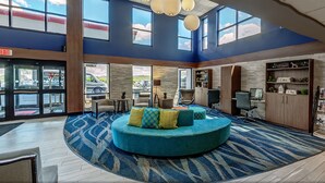 A lobby with a circular seating area, a reception desk, and a view of the parking lot.