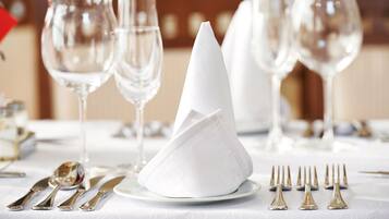 Une table dressée avec des serviettes blanches, des couverts en argent et des verres à vin transparents.