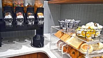 Una barra de desayuno con diversos alimentos y máquinas de café.