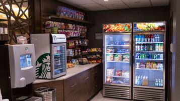 Ett Starbucks-kafé med en kaffemaskin för självbetjäning, kylda montrar och hyllor fyllda med snacks och drycker.