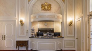 A reception area with a marble counter, two wall-mounted sconces, a clock, and a coat rack. - Beresford Arms Hotel (San Francisco)