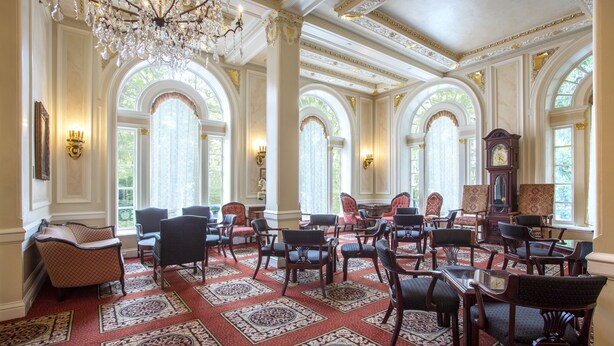 A grand room with ornate chandeliers, arched windows, and a variety of seating arrangements including chairs and tables. - Beresford Arms Hotel (San Francisco)