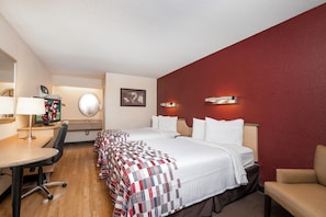 A hotel room with a bed, a desk, a chair, a TV, and a mirror.