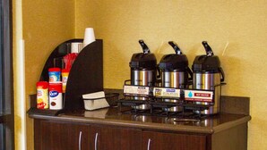 A coffee station with a coffee machine, sugar packets, and creamer containers. - Red Roof Inn Chesapeake Conference Center (Chesapeake)