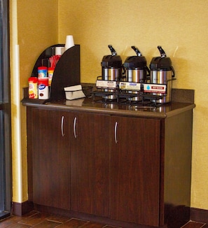 A coffee station with a coffee machine, sugar packets, and creamer containers. - Red Roof Inn Chesapeake Conference Center (Chesapeake)