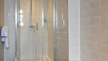 A modern bathroom with a glass-enclosed shower, a standalone bathtub, and a tiled wall.