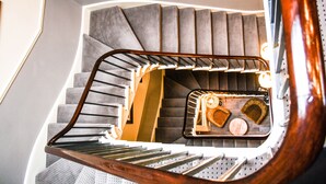A spiral staircase with a wooden handrail and grey steps.