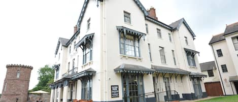 A traditional building with a white facade and dark trim, featuring outdoor seating and a sign indicating an outside dining area.