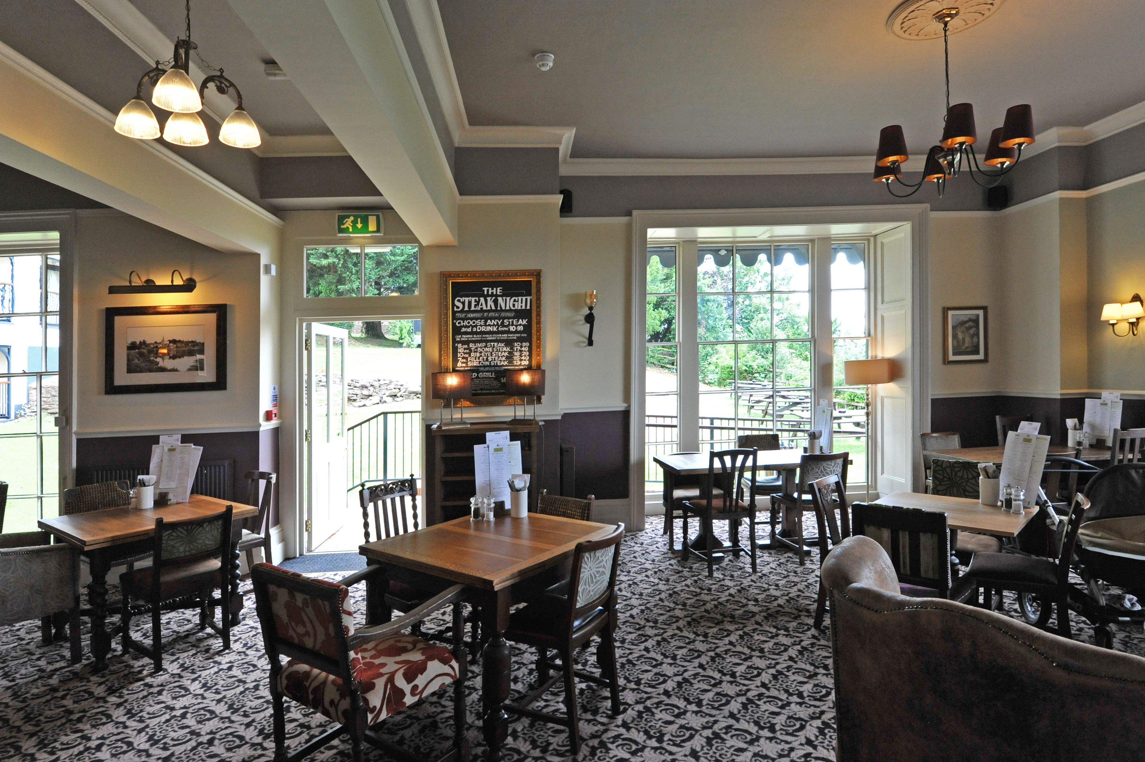 A restaurant interior with wooden tables and chairs, a chandelier, and a sign for 'The Steak Night'.