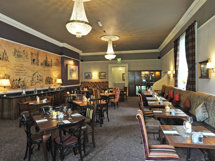 En restaurant med træborde og -stole, et barområde og et muralmaleri på væggen.