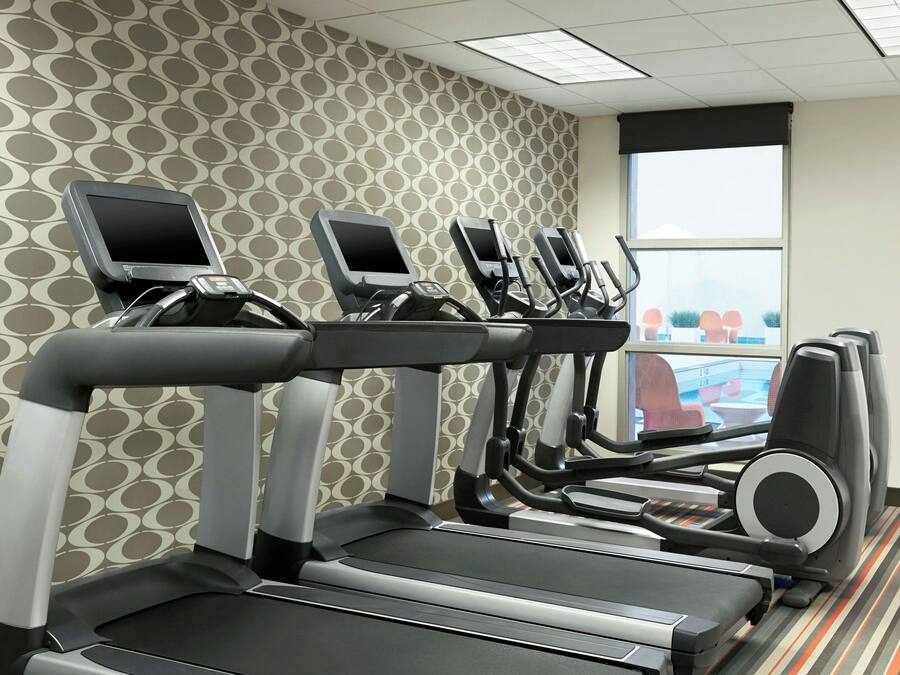 Un gimnasio con cintas de correr, elípticas y una pantalla de televisión.