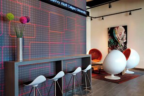 Un área de recepción moderna con una pantalla digital, taburetes de bar y asientos contemporáneos.