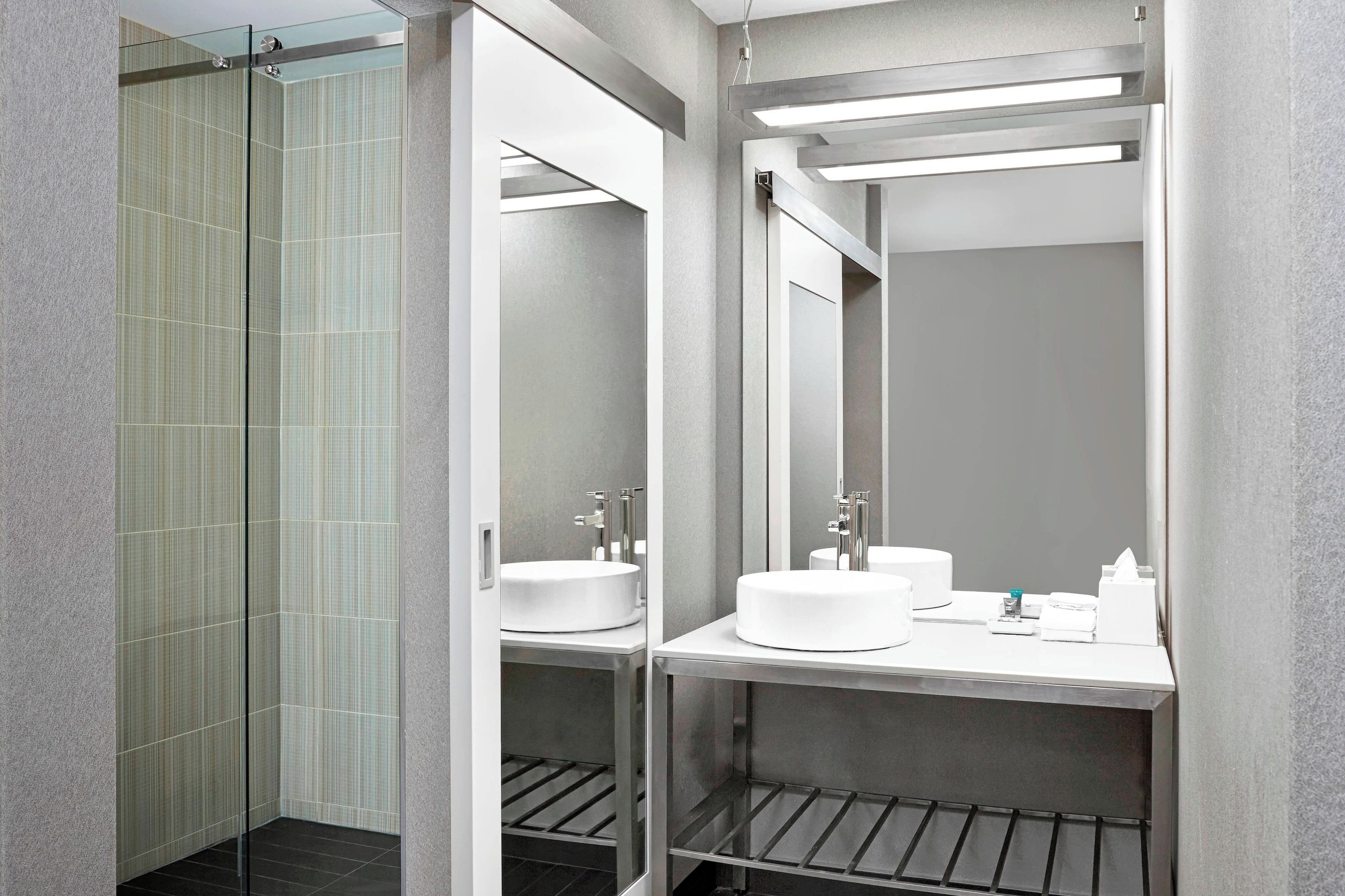 A modern bathroom with a glass shower enclosure, two sinks, and a large mirror.