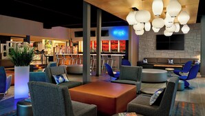 A modern lounge area with seating, a bar, and a TV screen. - Aloft by Marriott Calgary University (Calgary)