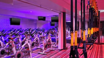 A gym with stationary bikes arranged in rows, a patterned carpet, and a large mirror.